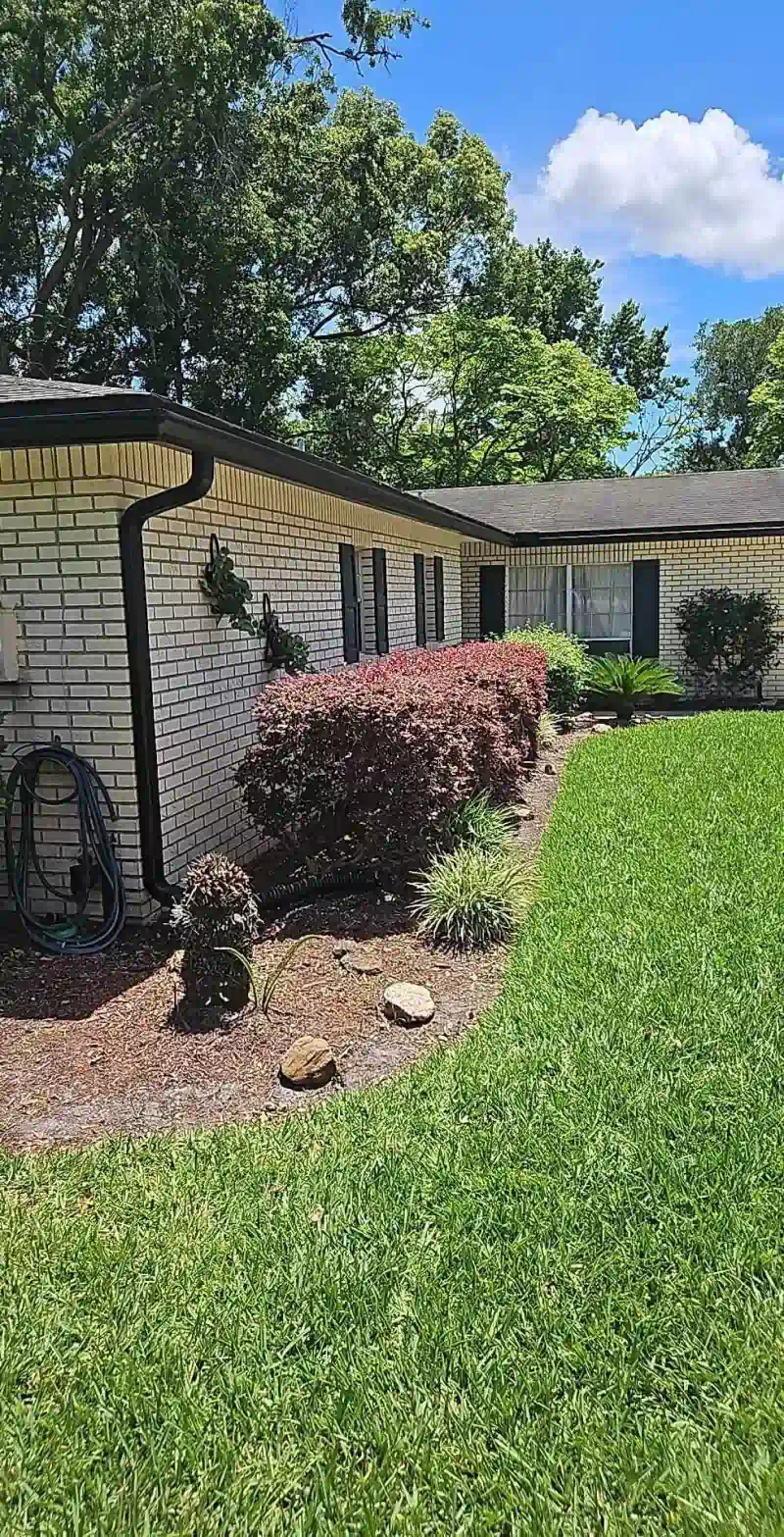 A white brick house with a large lush green lawn in front of it.