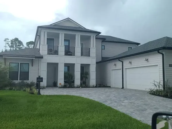 A large white house with two garages and a large driveway.
