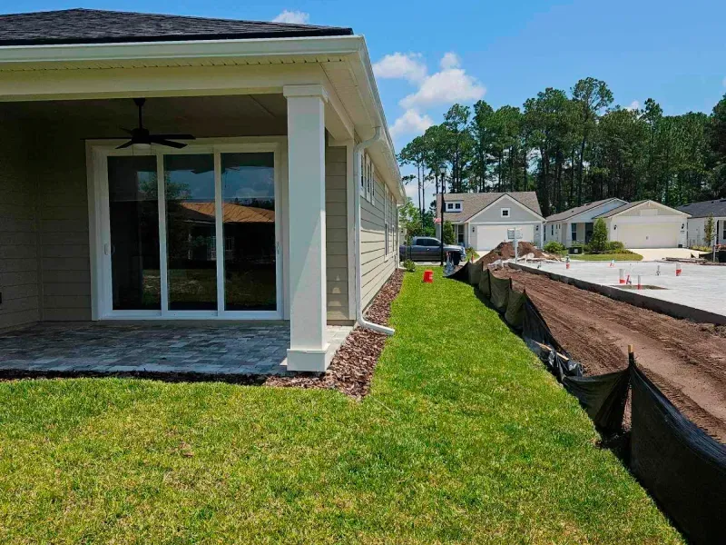 A house is being built in a residential area with a lot of grass and dirt.