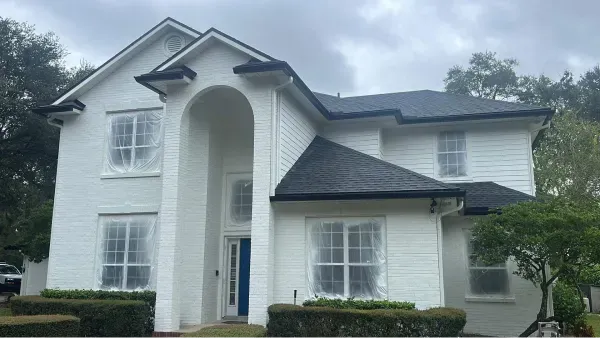A large white house with a black roof and a blue door.