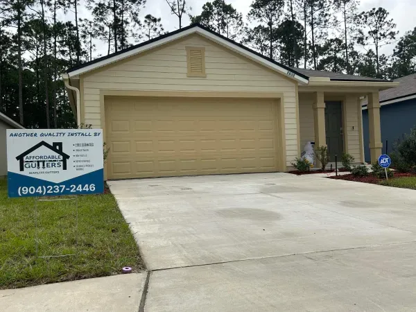 A house with a garage door and a sign in front of it.