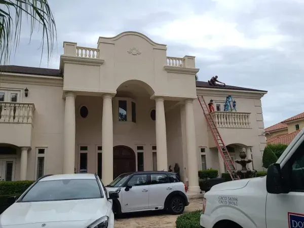 Two white cars are parked in front of a large white house.