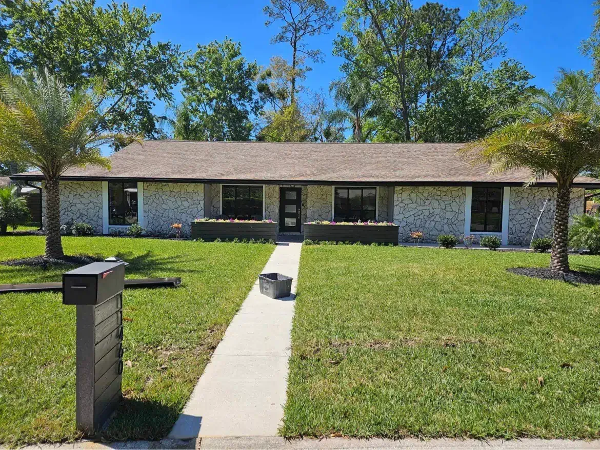 A house with a lush green lawn and palm trees in front of it.