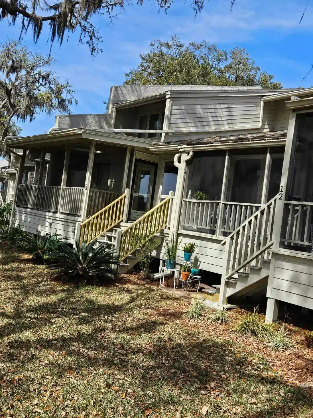 A large white house with a screened in porch and stairs.