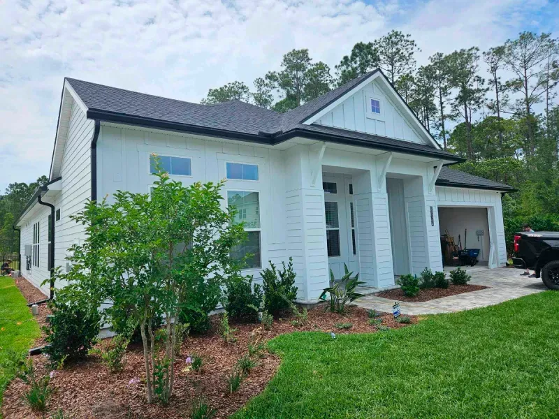 A white house with a black truck parked in front of it.