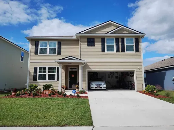 A large house with a car parked in the driveway.