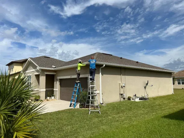 Two men are painting the roof of a house.