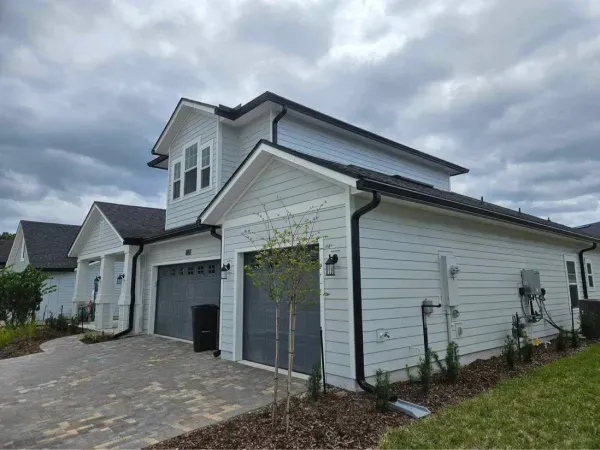 A white house with two garages and a gray garage door.