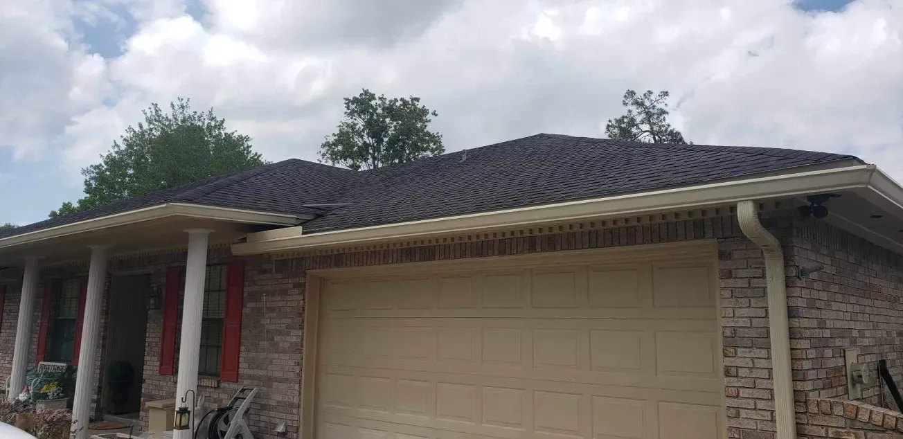A brick house with a garage door and a black roof.