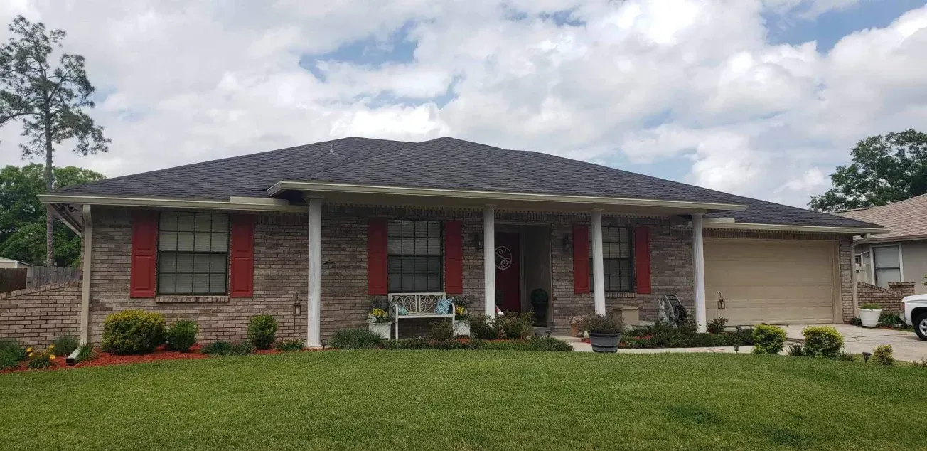 A brick house with red shutters and a white truck parked in front of it.