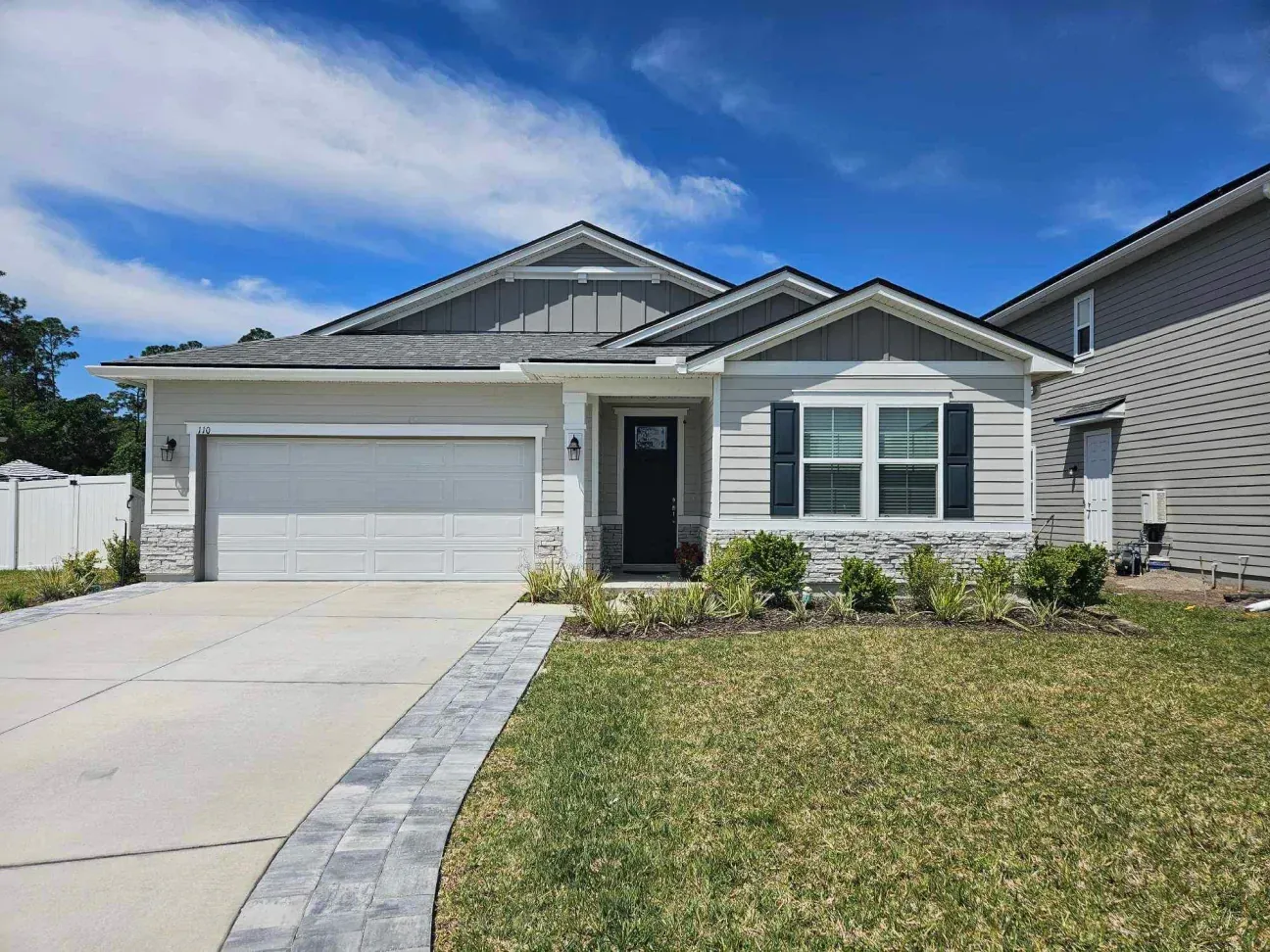The front of a house with a large garage and a lush green yard.