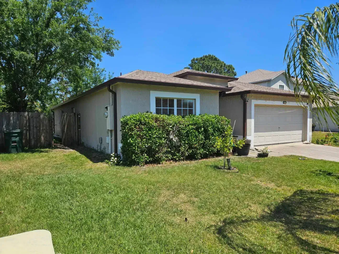 A house with a garage and a lot of grass in front of it.