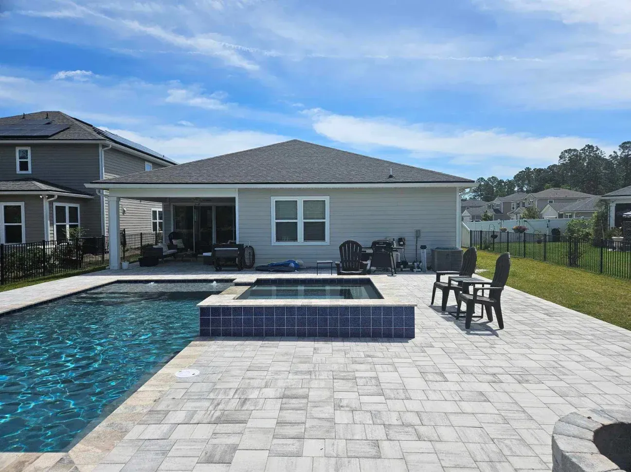 There is a large swimming pool in the backyard of a house.