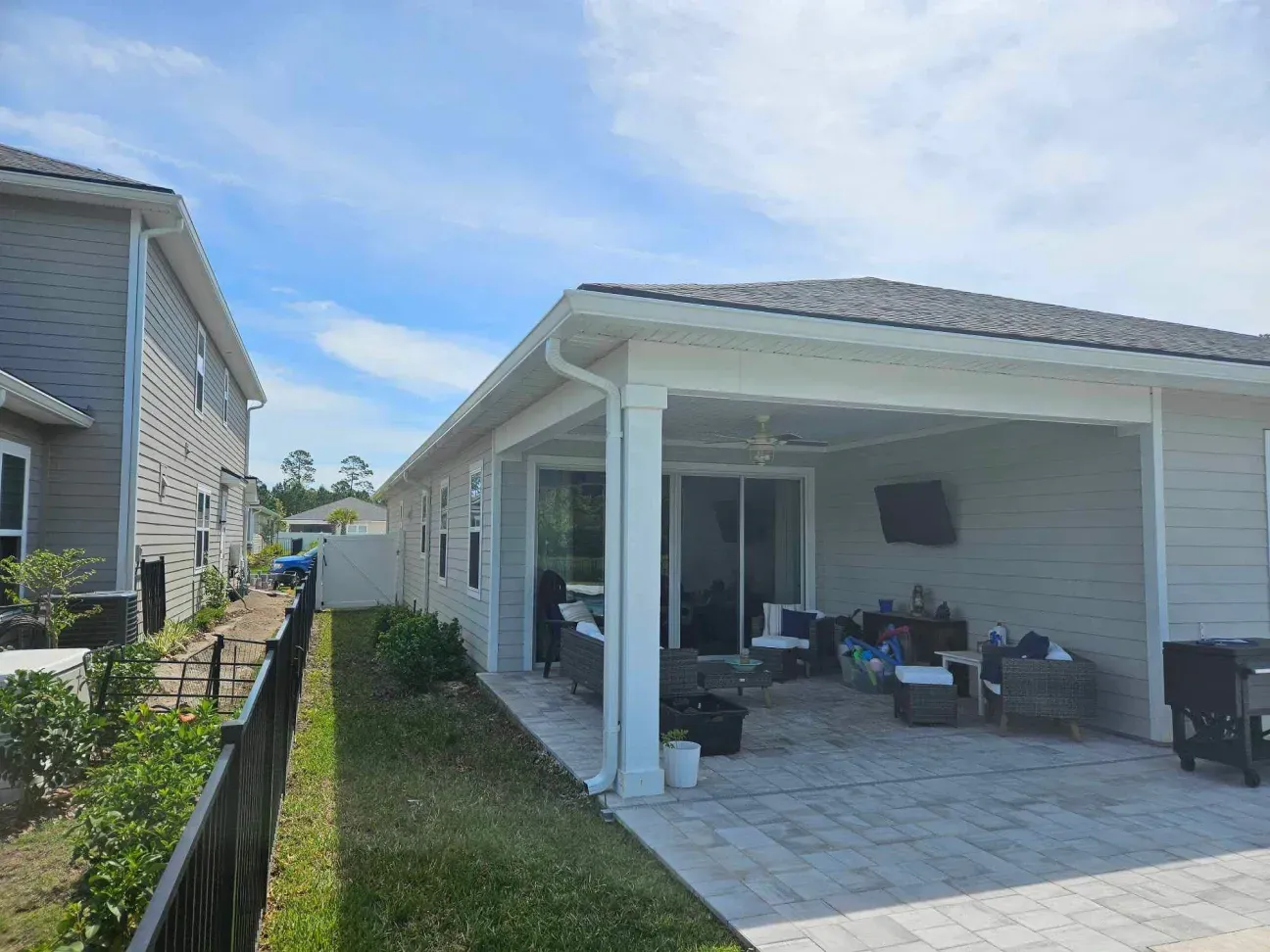 A house with a covered patio and a fence in front of it.