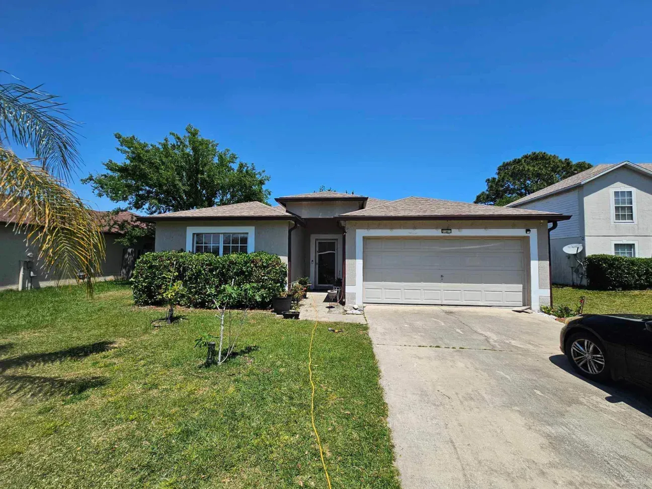 A house with a car parked in front of it on a sunny day.