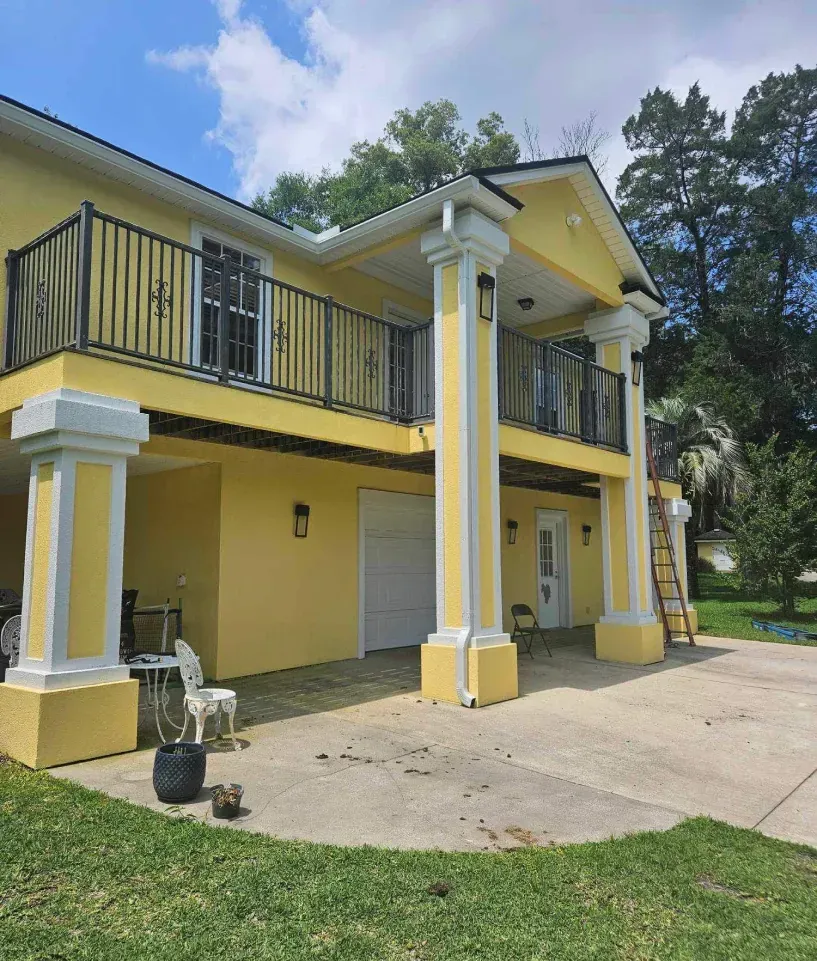 A large yellow house with a balcony and columns