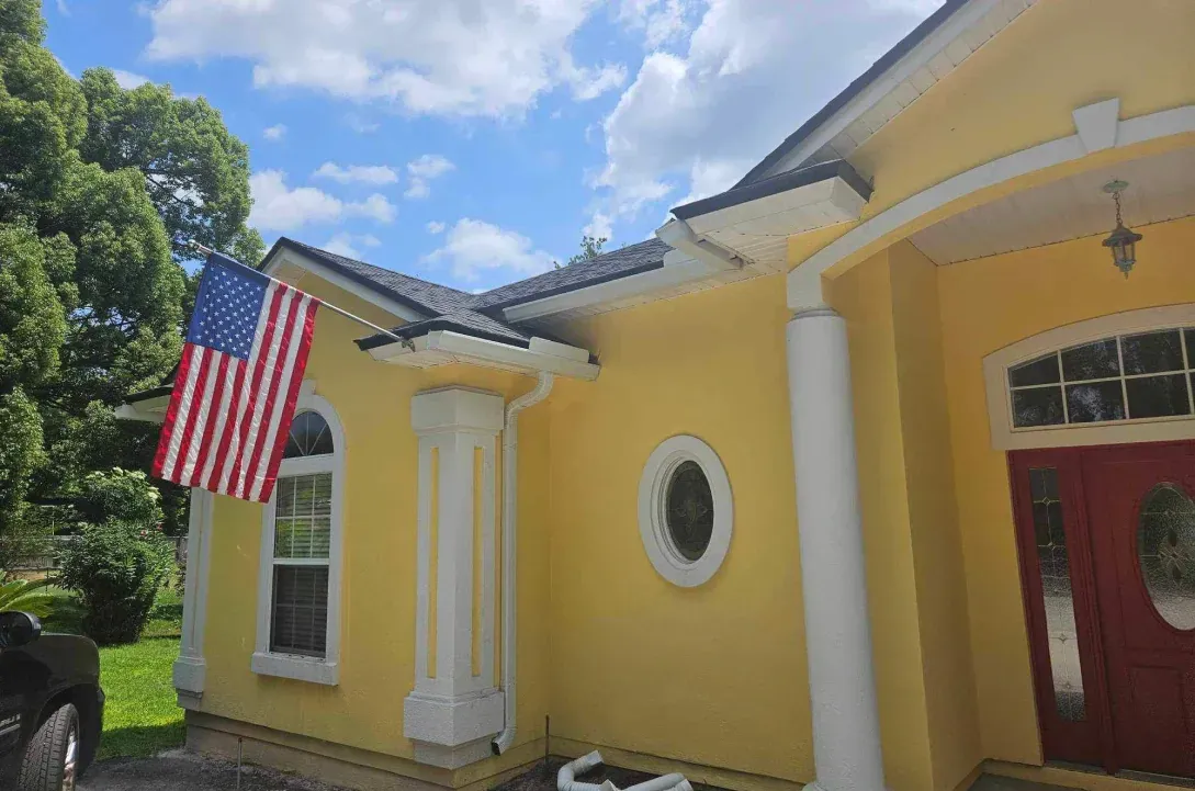 A yellow house with an american flag hanging from the side of it.