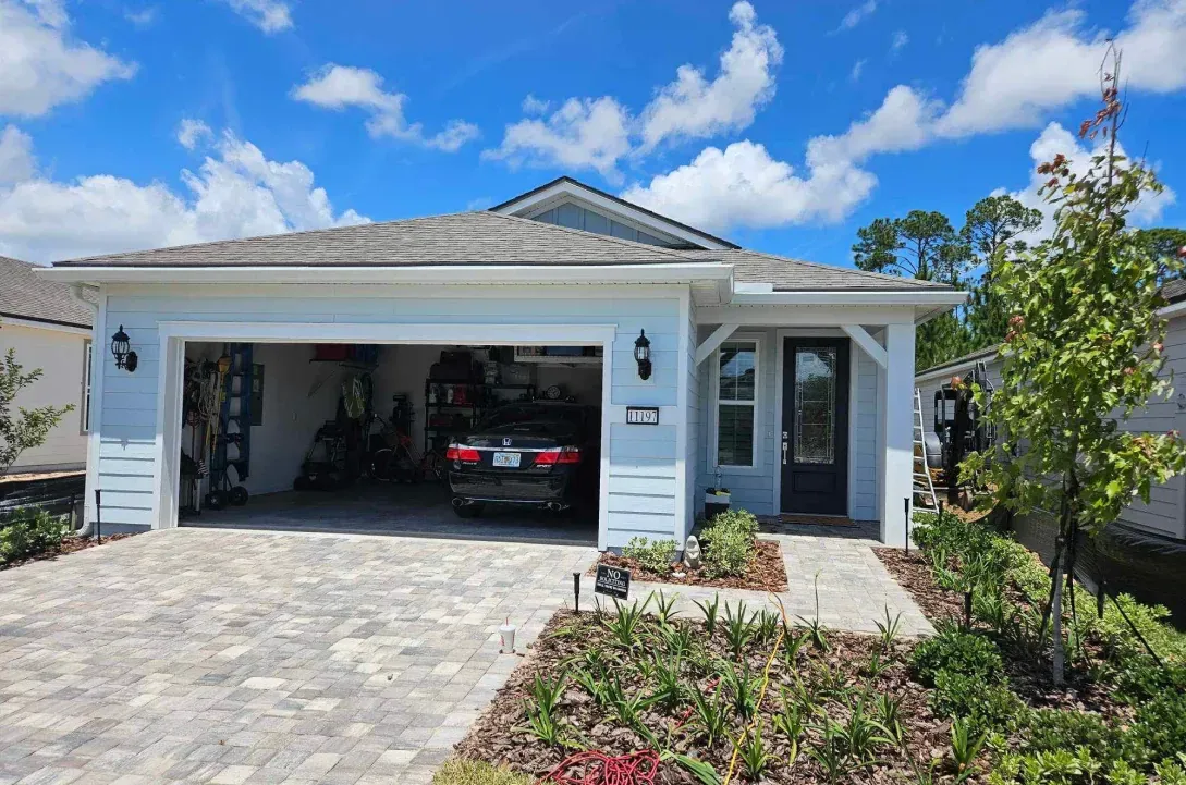 A car is parked in a garage in front of a house.