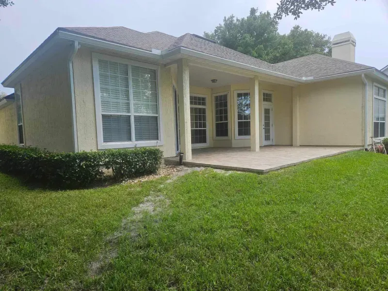 The back of a house with a patio and a lot of windows.