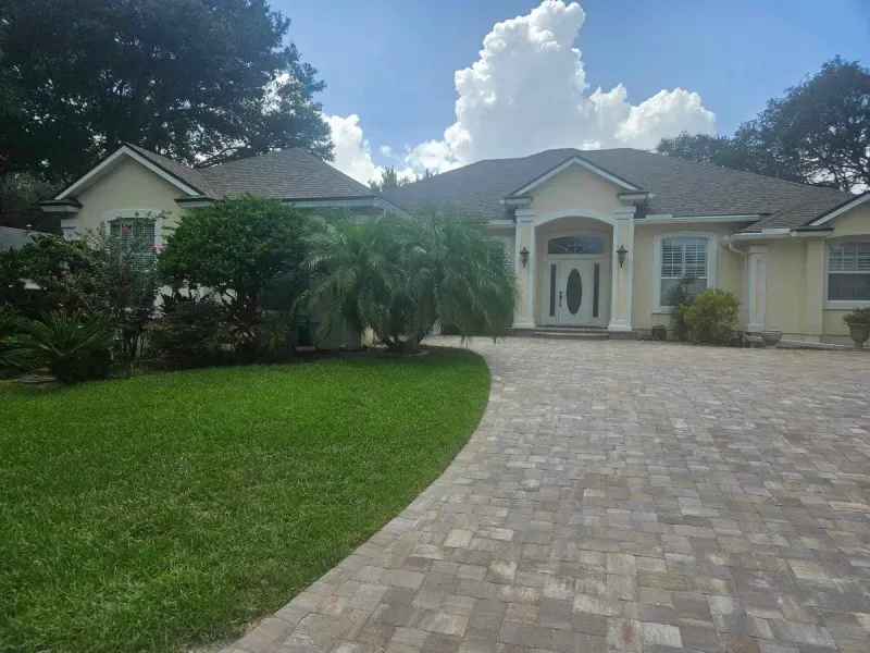 A large house with a brick driveway leading to it