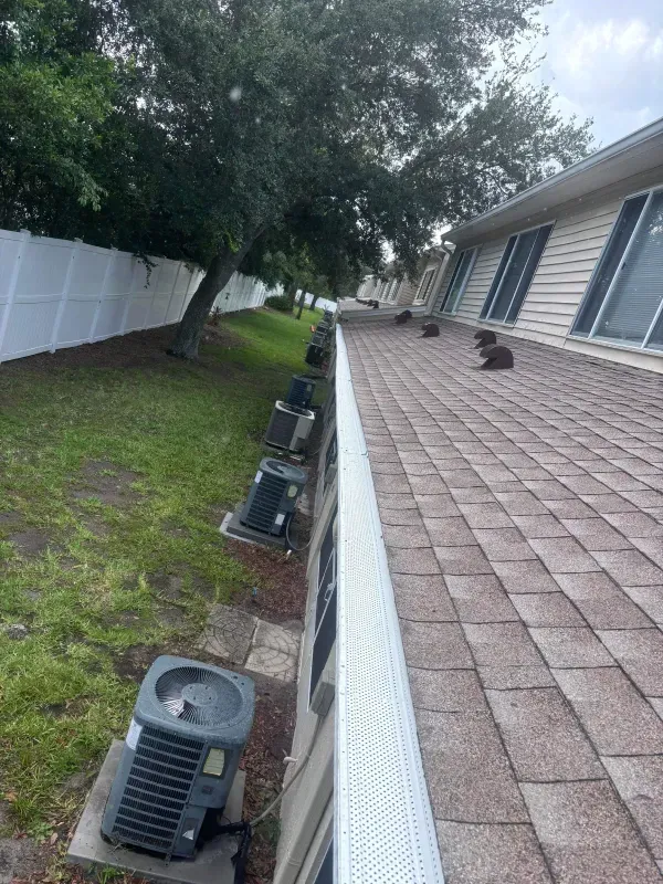 A row of air conditioners are sitting on the roof of a house.