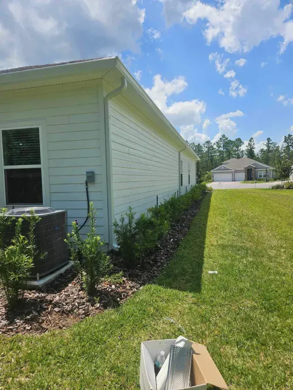 A white house with a box in front of it in the grass.