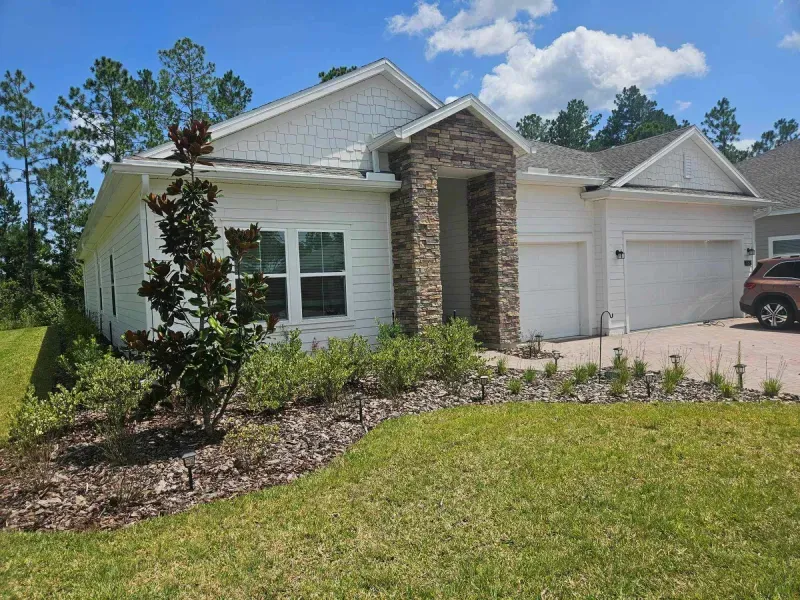 A white house with a car parked in front of it.