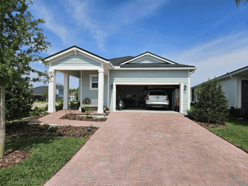 A car is parked in a garage in front of a house.