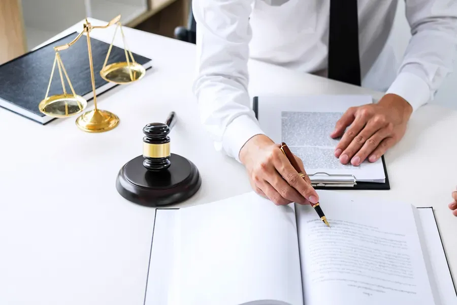 A lawyer is sitting at a desk with a gavel and scales of justice.
