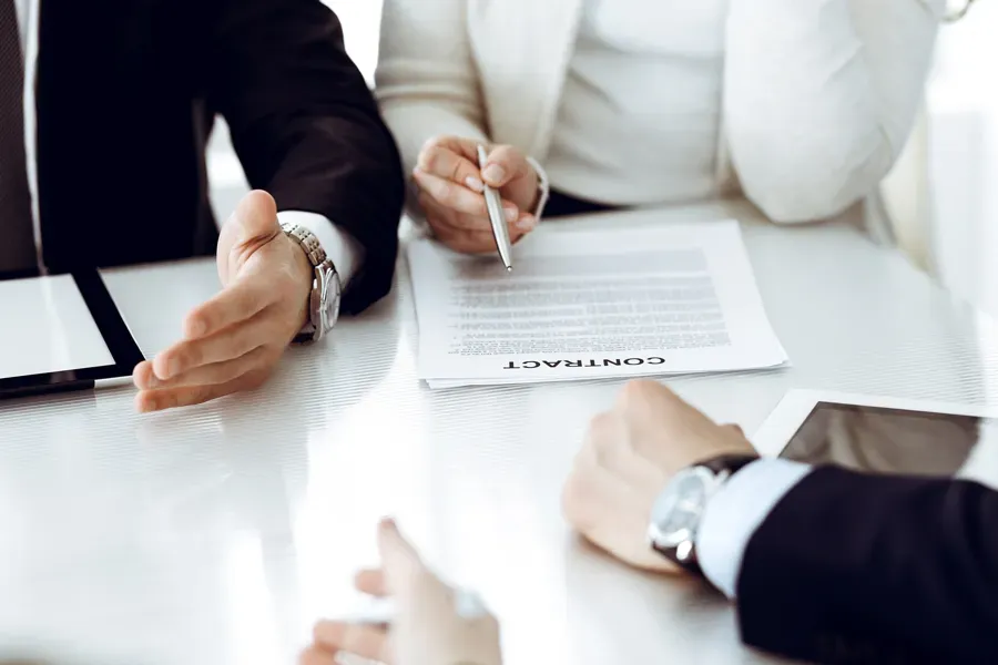 A man and a woman are sitting at a table signing a contract.