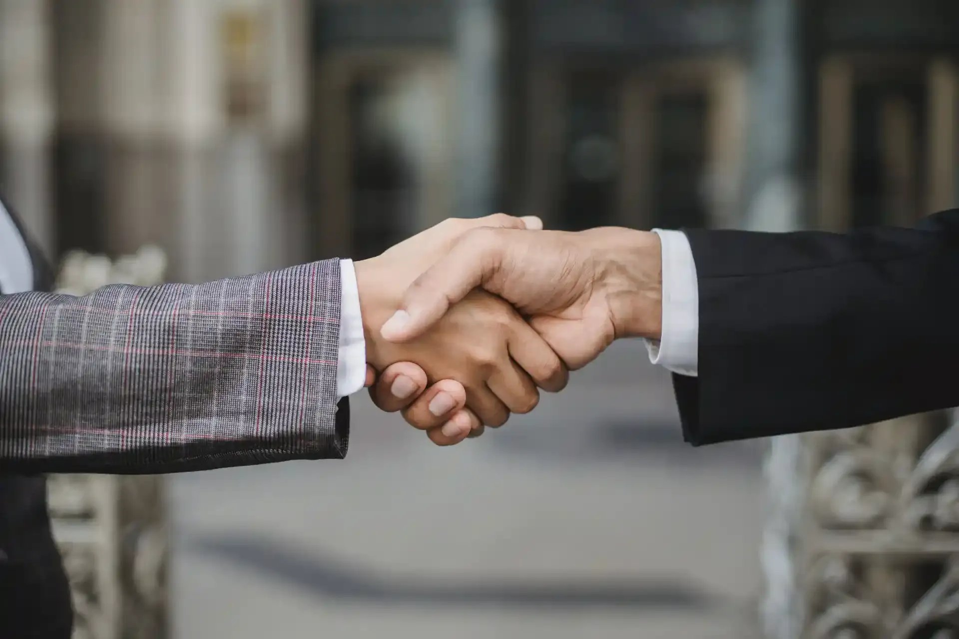 A man and a woman are shaking hands over a table.