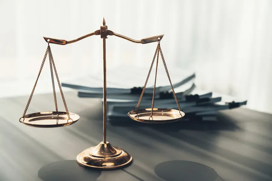 A scale of justice is sitting on a wooden table.