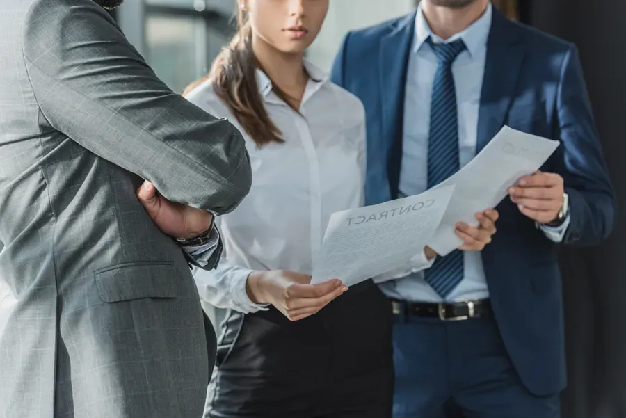 A group of business people are standing next to each other looking at a piece of paper.