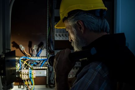 Person in plaid shirt and gloves installing light wood flooring.