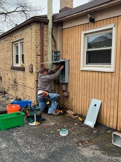 Two workers installing an AC unit outside on a wet surface.