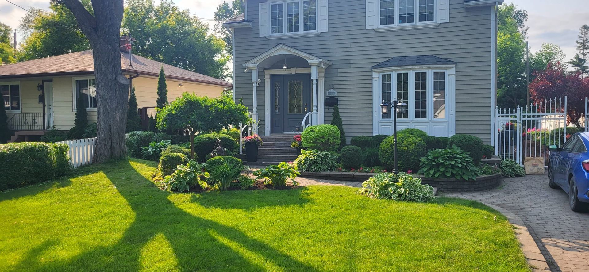 A large house with a blue car parked in front of it.