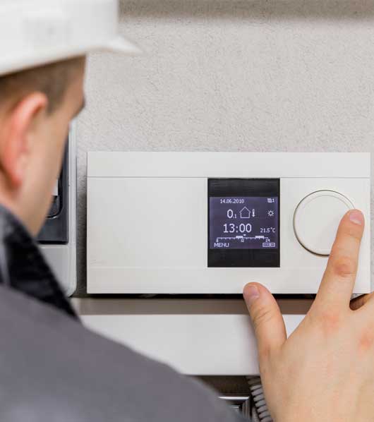 Man Adjusting Thermostat — Zachary, LA — Hughes Mechanical Contractors