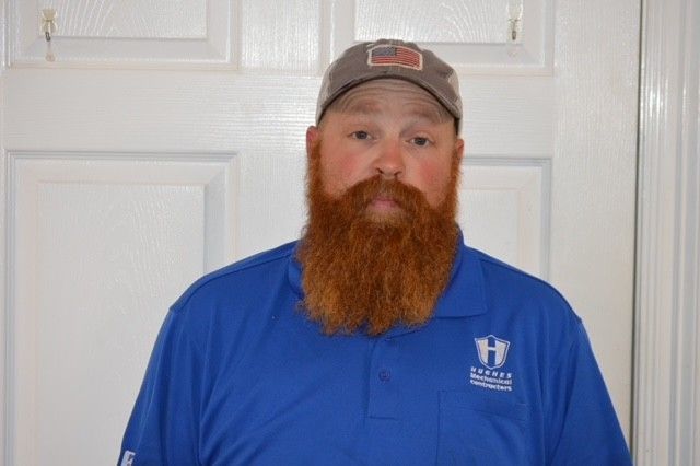 Man with a red beard wearing a blue polo shirt and a cap with a small American flag patch.