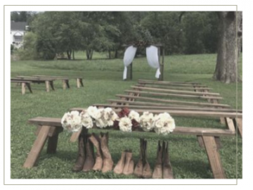 Outdoors memorial with white flowers and boots lined before wooden benches in a grassy park