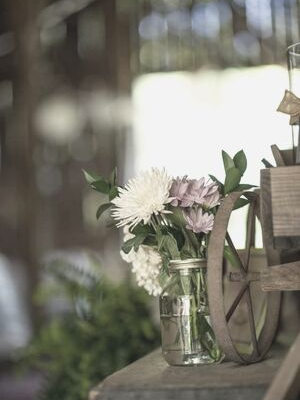 Flowers in glass vases on a wooden table, with soft blurred background lighting.