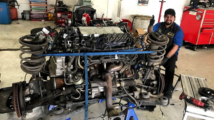 Mechanic sitting next to engine | Friendly Auto Centers