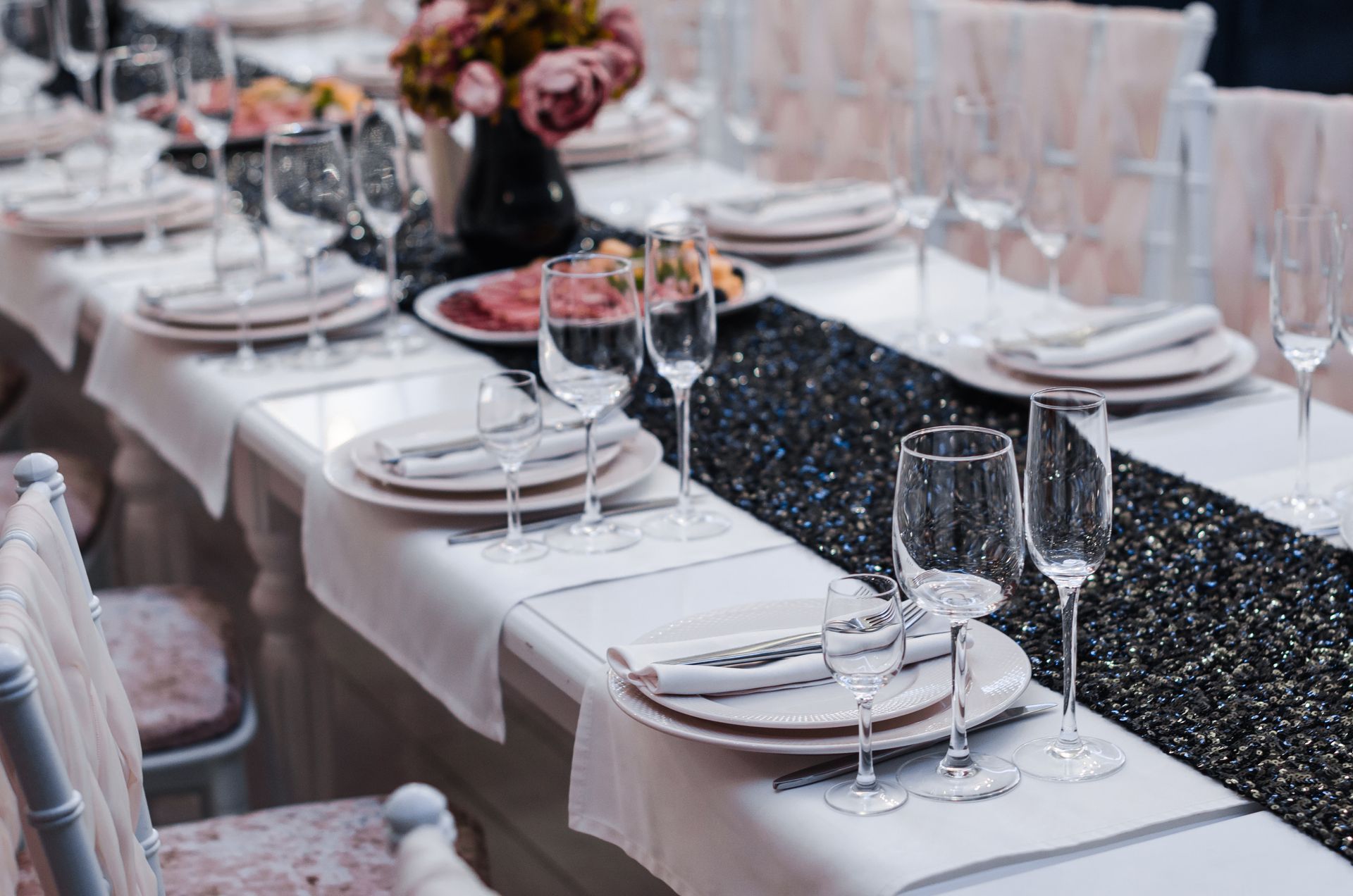 Formal dining table set with white linens, dishes, and champagne flutes.