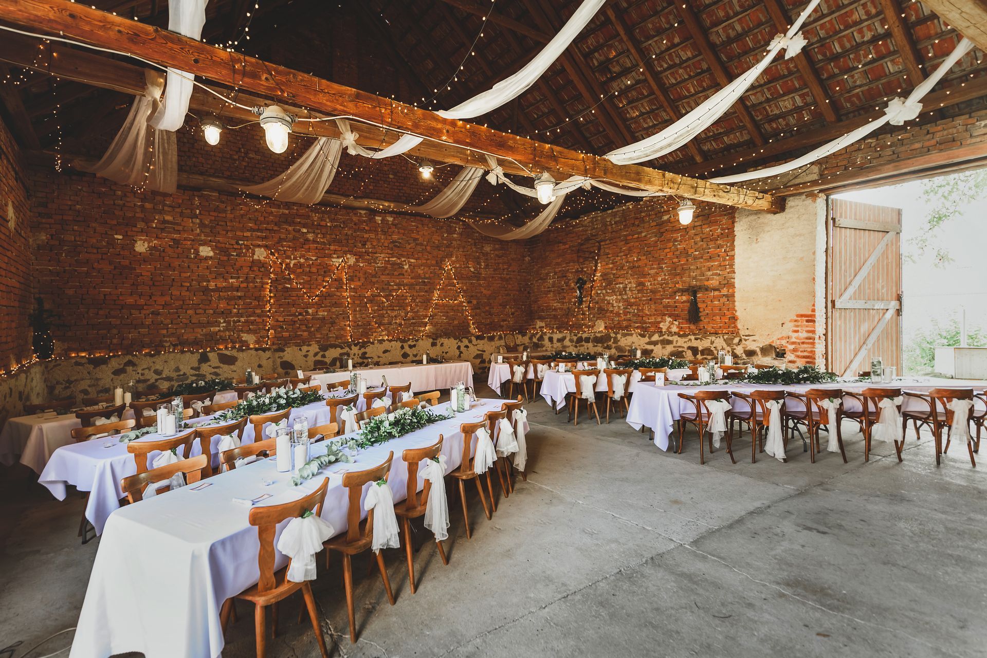 Barn interior with tables set for a wedding reception.