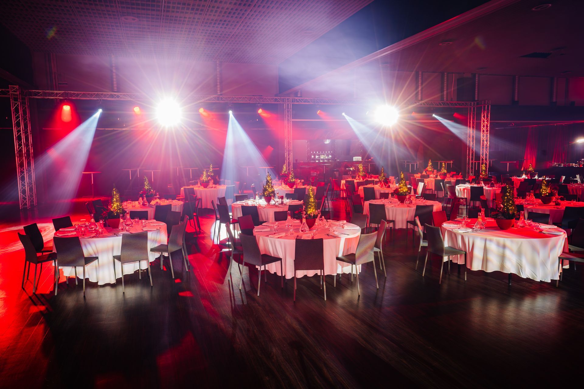 Event space with round tables set with white linens; red and white lighting.