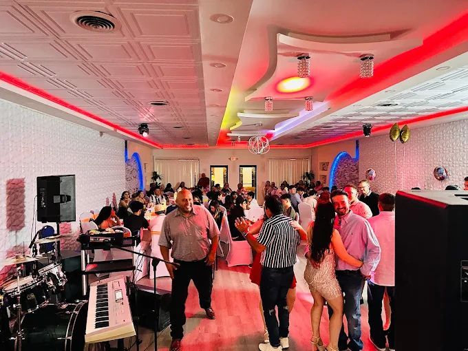 People dancing and socializing at a party in a decorated hall with a band playing.