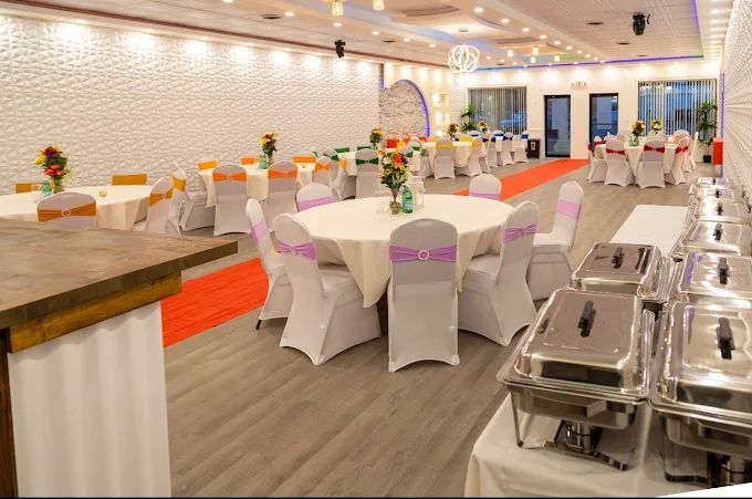 Banquet hall with tables set for a meal, a buffet line in the foreground.