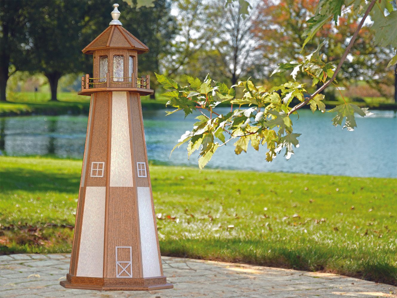 Brown and white lighthouse statue on a stone path, with a pond and trees in the background.