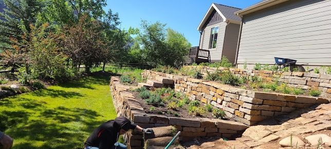 A man is working on a stone wall in front of a house.