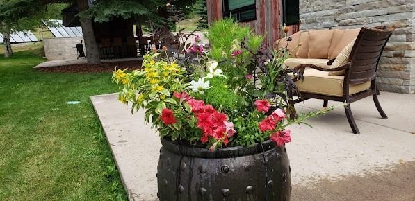 A planter filled with flowers is sitting on a patio next to a couch and chair.
