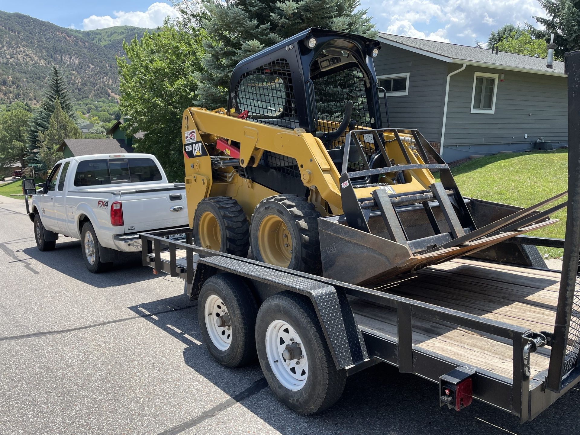 A white truck is towing a bulldozer on a trailer.